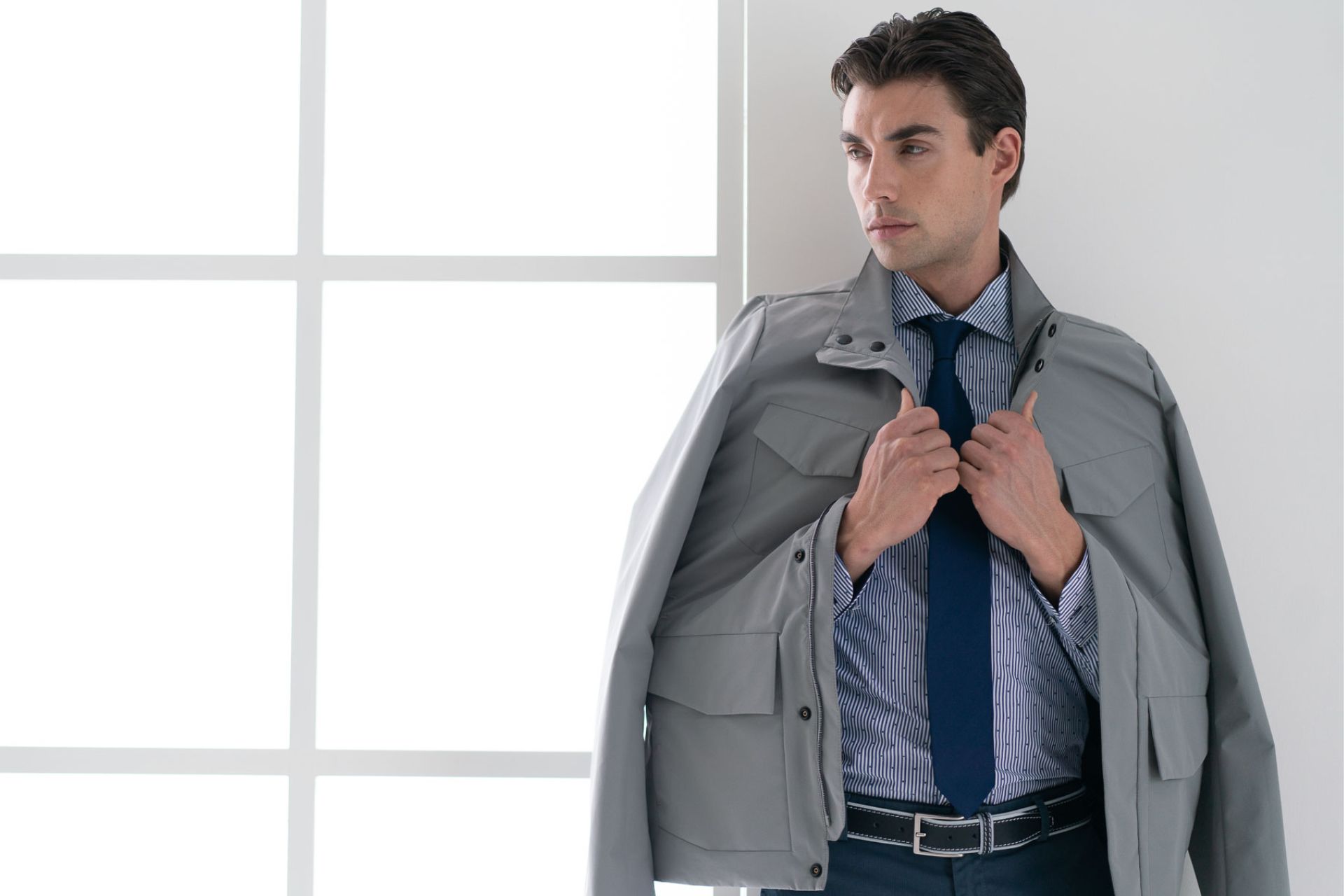 ragazzo con giubbino field jacket grigio, camicia fil coup&eacute; e cravatta